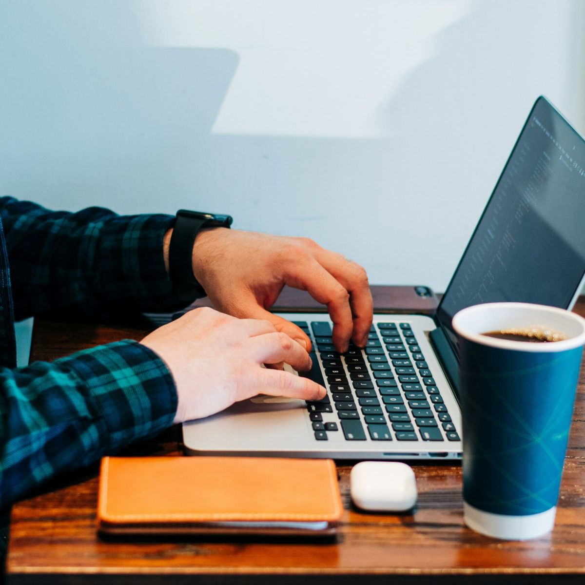 Mensch vor einem Computer, daneben ein Kaffeebecher
